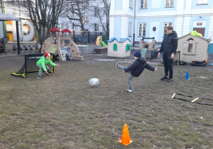 Chłopiec wykonuje strzał piłką do bramki, w której broni kolega.