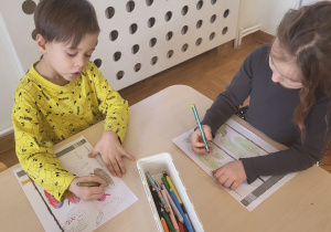 Dwoje dzieci wykonuje kartę pracy - kolorują odpowiednie sylaby.