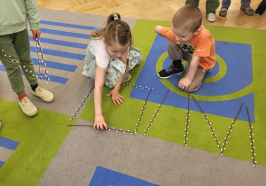 Dzieci układają wyraz WIOSNA z gałązek z baziami.