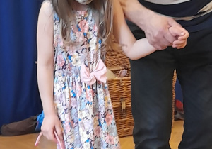 Dziewczynka podczas warsztatów teatralnych prezentuje maskę czarownicy.