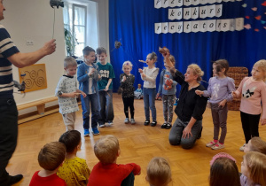Dzieci prezentują różne rodzaje lalek teatralnych.