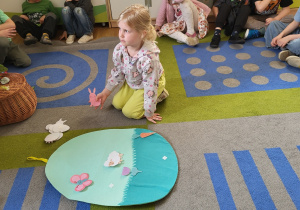 Dziewczynka układa elementy Wielkanocne na dużym flanelowym jaju.