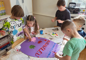 Praca zbiorowa. Dzieci malując farbami ozdabiają jajo z brystolu wg własnego pomysłu.