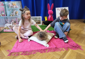 Dwoje dzieci głaszcze kurkę Halinkę.