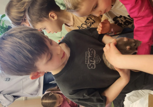 Chłopiec pokazuje szczurka dzieciom.